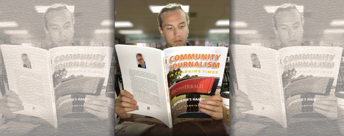 Journalist in coffee shop studying Community Journalism In Changing Times. Learning as he works: on the go.